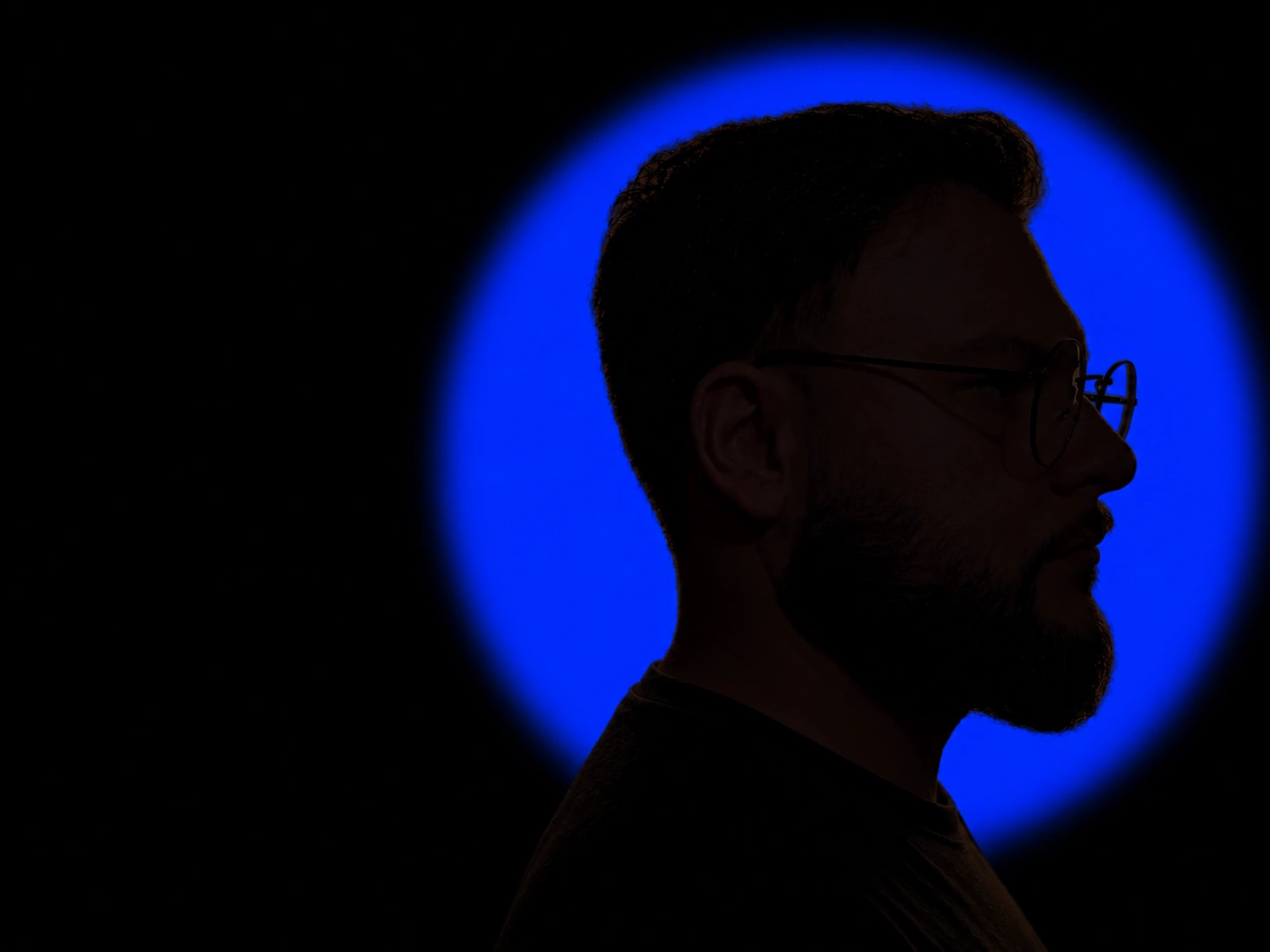 Christian Paes de perfil, com um círculo azul ao fundo.
