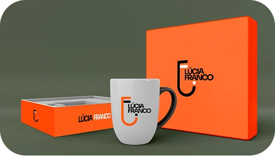 Caneca, caixa e caderno com a marca Lúcia Franco.